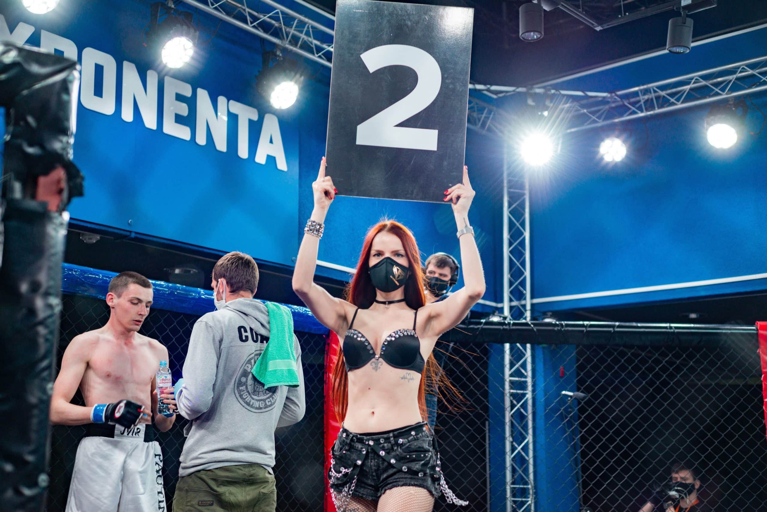 mma, girl model in a black leather suit and medical mask in the ring, in the octagon, announcement of the round