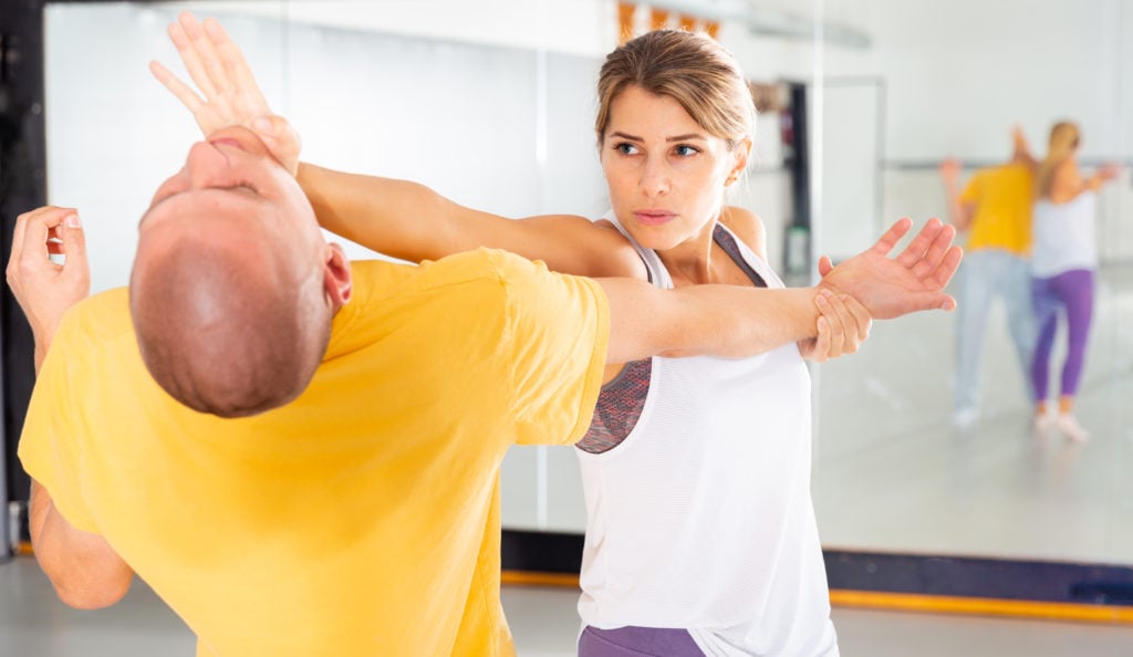 Young woman paired up with male partner in self defense training, practicing basic palm strike